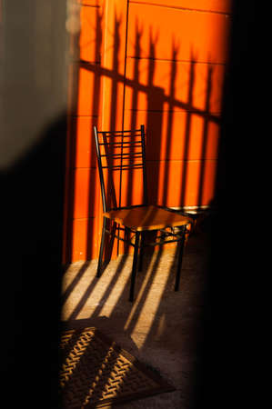 Silhouette of a chair in front of an orange wall.の写真素材