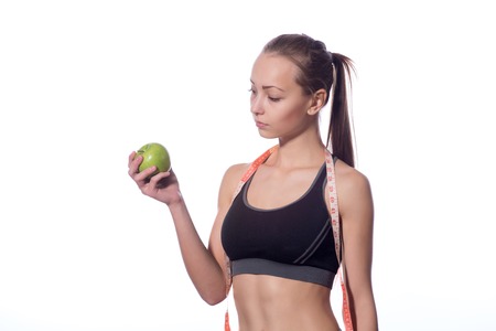 Fitness woman in sports style with a measuring tape standing on a white backgroundの写真素材