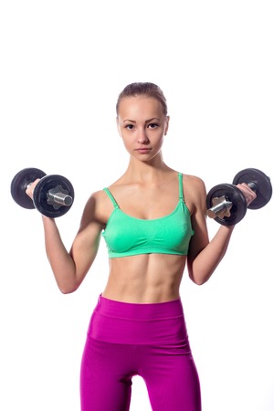 Young girl doing exercises with dumbbells. White background.の写真素材