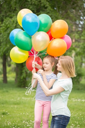 happy mother and daughter playing in the park with balloonsの写真素材