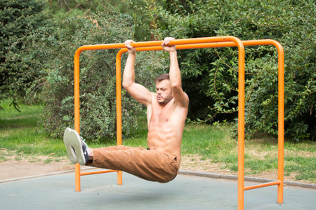 fitness, sport, exercising, training and lifestyle concept - young man doing triceps dip on parallel...