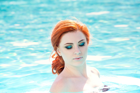 Portrait of a beautiful woman getting out of a swimming pool. beautiful long hair tanned model posing by blue pool water. Outdoor summer portrait of sexy girl in sunglasses. woman in red swimsuit.の写真素材