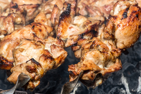 Grilled kebab cooking on metal skewer closeup. Roasted meat cooked at barbecue. BBQ fresh beef meat chop slices. Traditional eastern dish, shish kebab. Grill on charcoal and flame, picnic, street foodの写真素材