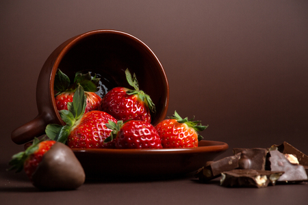 fresh juicy organic strawberries in an old clay bowl on a brown backgroundの写真素材