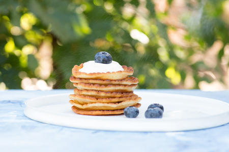 A stack of delicious pancakes with sour cream, raspberries and blueberries on a light background. with copy spaceの写真素材