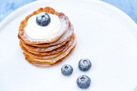 A stack of delicious pancakes with sour cream, raspberries and blueberries on a light background. with copy spaceの写真素材