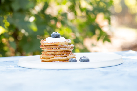A stack of delicious pancakes with sour cream, raspberries and blueberries on a light background. with copy spaceの写真素材