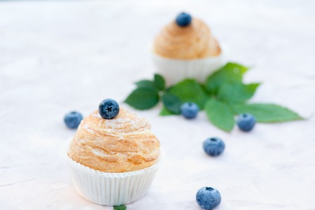 Fresh baked golden muffins with blue berries on rustic wooden background shot in natural lightの写真素材