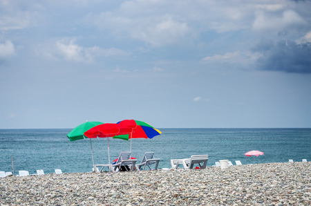 Sun umbrellas stuck in a pebble beach with blue seaの写真素材