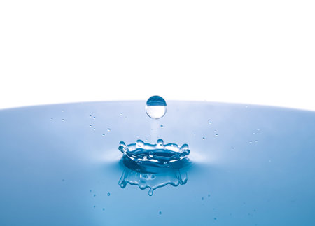 Water droplets fall closely into the deep blue water, making it the perfect water splash center in...