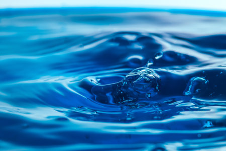 Dark blue water droplets splash close up on the water surface. It creates a water wave and a perfect crownの写真素材