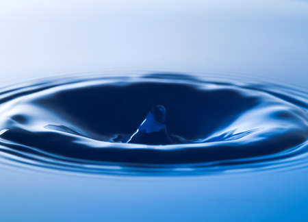 the drop of blue water fell, causing a splash on the water surface. Create water waves and a crown that is perfect in nature.の写真素材
