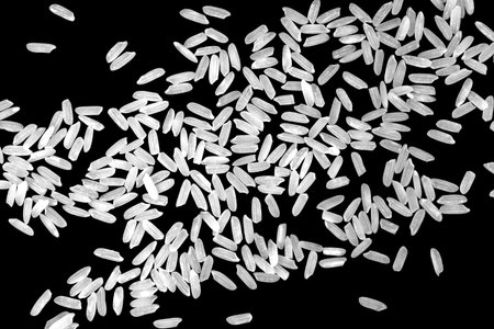 Top view, close-up. A pile of white uncooked rice grains, lying flat. Isolated on black background.