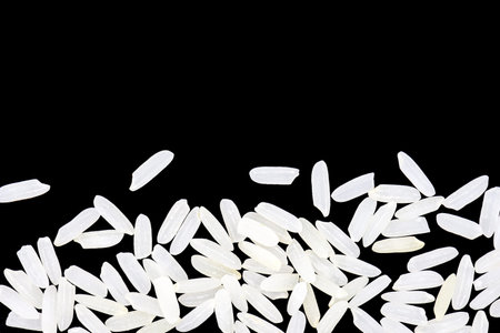Top view, close-up. A pile of white uncooked rice grains, lying flat. Isolated on black background.
