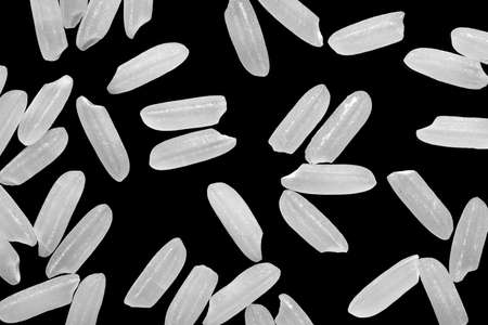 Top view, close-up macro shot. Uncooked long white brown rice grains, lying flat. Isolated on black background.の写真素材