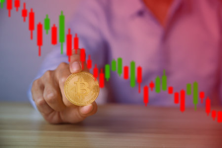 An investor catches a Bitcoin coin with a graph chart showing the decline. Price collapse concept cryptocurrency coin downtrendの写真素材