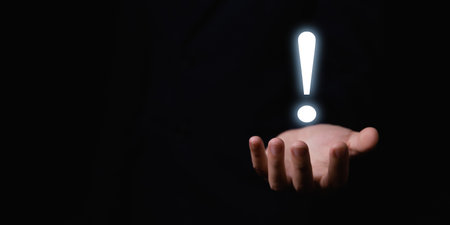 The businessman's hand shows a white exclamation mark. business development concept, error warning, notification, maintenance, and finding a solution. dark background with copy spaceの写真素材