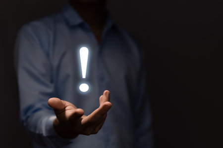 The businessman's hand shows a white exclamation mark. business development concept, error warning, notification, maintenance, and finding a solution. dark background with copy spaceの写真素材