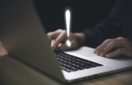 Businessman using laptop showing exclamation mark. business development ideas Error warning, notification, maintenance and finding solutions dark background with copy spaceの写真素材