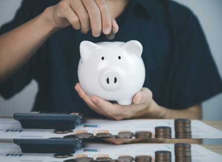 man puts coins in pig piggy bank. concept of Saving bank accounts and investing funds to maximize profits. Growing business investment and future successの写真素材