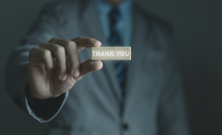 Businessman holding wooden block showing a message with word thank you letter writing ideas congratulations thank you copy spaceの写真素材