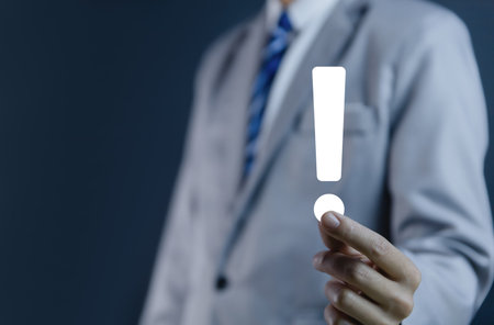 businessman hand showing exclamation point business development ideas Warning of errors, dangers, alerts, maintenance, And finding solutions. Important information. Dark background with copy space.の写真素材