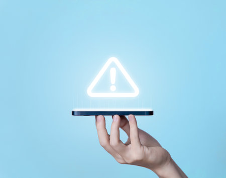 Hand-holding smartphone showing warning triangle and exclamation mark icon Warning about a dangerous problem Server error. maintenance concept, precaution, network security, internet technologyの写真素材