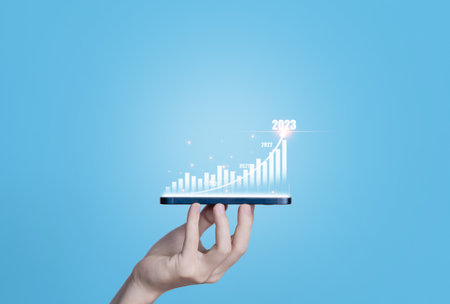 Hand-holding smartphone showing positive technology chart Digital stock market strategy effective investment ideas exchange rate economic development stock growth and business success goals 2023の写真素材