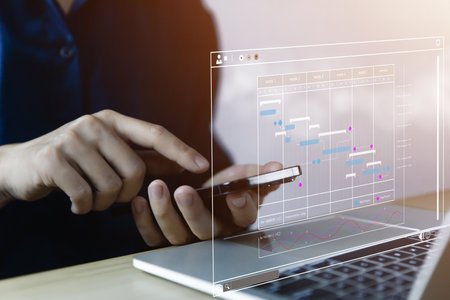 Male manager managing business planning project schedule in the office. Gantt chart showing on virtual screen. business people manage computer data in digital technology on the internetの写真素材