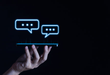 Businessman hand holding a smartphone showing message chat icon Digital blank comment. Balloon Speech bubble concept. Communication Business. Space for text. dark backgroundの写真素材
