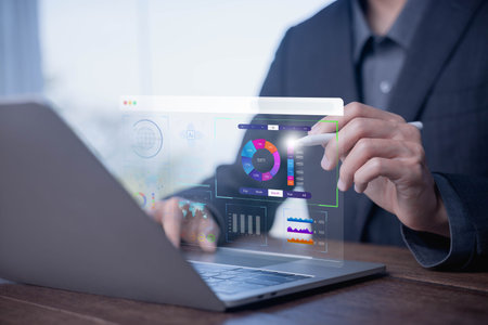 Data analytics dashboard concept with a businessman using a laptop to visualize charts, graphs, and...