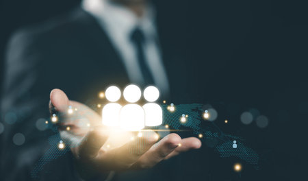 Businessman holding glowing people icon over digital world map. Concept of global HR, team management, remote workforce, networking, talent acquisition, and international human resource strategy.の写真素材