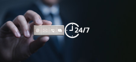 customer support concept. a businessman holding a wooden block showing communication icons, symbolizing online service, call center, email, chat assistance, and continuous business support.の写真素材