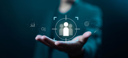 Businessman hand holding digital target audience icon, symbolizing customer focus, market analysis, audience segmentation, business strategy, and data-driven decision-making in corporate marketing.の写真素材