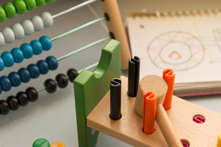 Close up capture of toys of baby on table, wooden hammer, colorful sticks, abacus and notebook in...