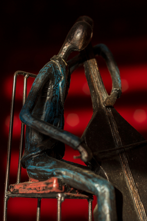 Close up capture of iron model of violin player in dramatic light on red backgroundの写真素材