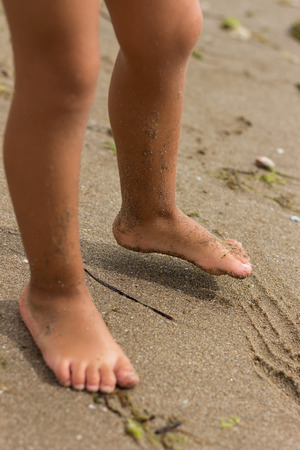 Bare feet of child playing on sandy beachの写真素材