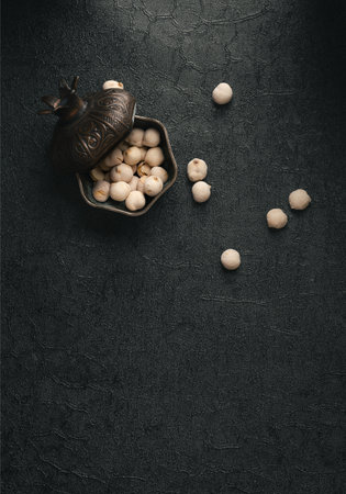Pepper seeds in a metal bowl on a black textured backgroundの写真素材