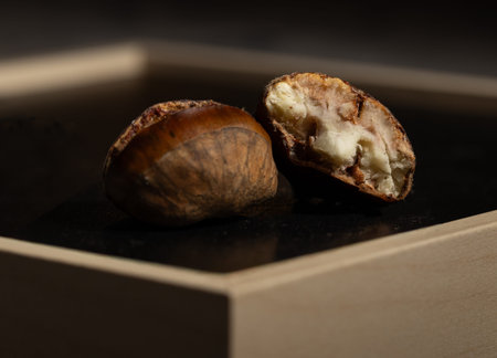 close-up shot of a roasted chestnut split open, revealing its soft, creamy interior under warm,...