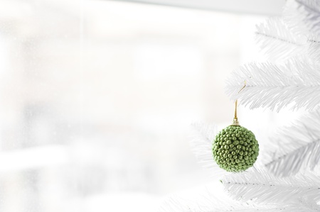 Green bauble hanging on white Christmas Three with winter scene behind the windowの写真素材
