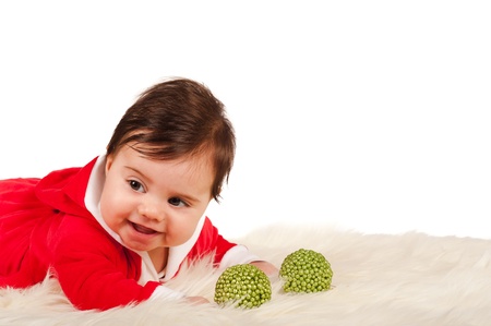 Baby liyng on blanket smiling with two green christmas baubleの写真素材
