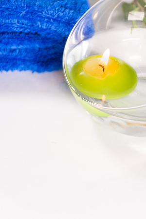 Lit candle with a blue towel, in a bathroom or a spa, with white backgroundの写真素材