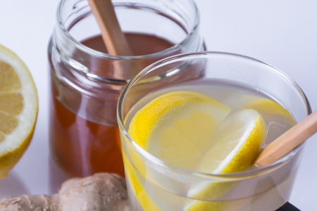 Still life of ginger infusion with ingredients, lemon and honey on a white background and on a reflecting baseの写真素材