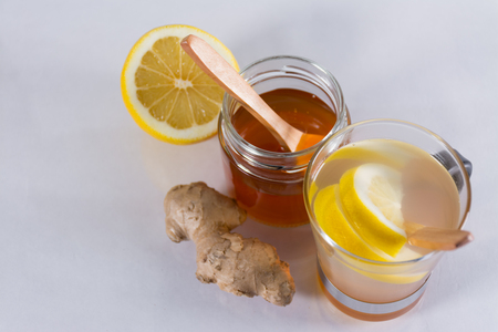Still life of ginger infusion with ingredients, lemon and honey on a white background and on a reflecting baseの写真素材