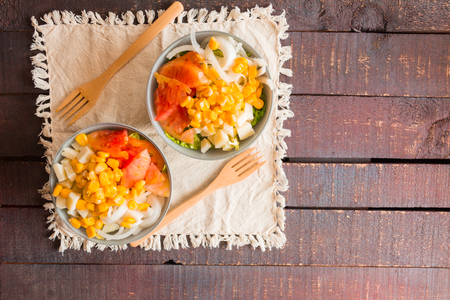 Fresh salad in two bowls on a wooden tableの写真素材