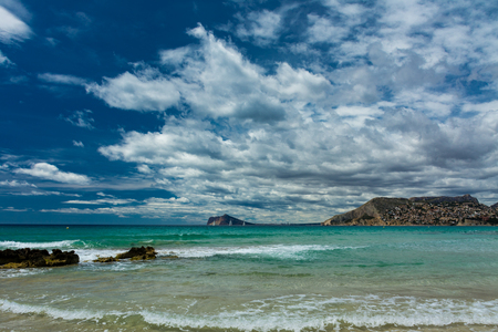 Cantal Roig beach in Calpe, Alicante, Spain. Benidorm city at background, and some residential housesの写真素材