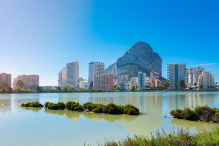 The rock of Ifach, Calpe, Alicante, Spain, next to the apartment buildings. Their reflection in the water of the saltworksの写真素材