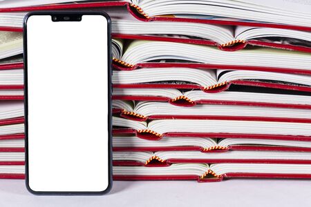Pile of opened books with a smartphone with white screenの写真素材