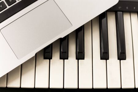 Keyboard and computer. Concepts of learning to play music online at home, working from home, self-taught or autodidactの写真素材