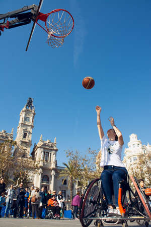 Valencia, Spain. February 15, 2020 - Adaptive sports day. An adaptive basketball player throwing the ball into the basket on the prepared court in the town hall squareのeditorial素材